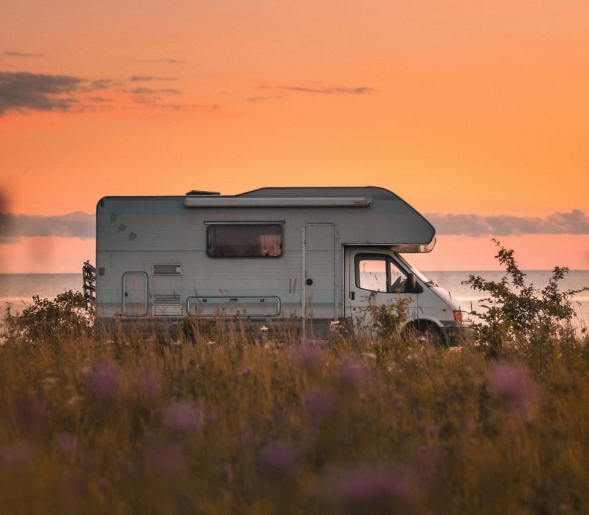 Motor home RV parked in a field at sunset