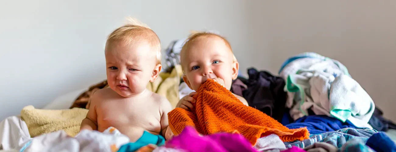 two babies on a pile of laundry