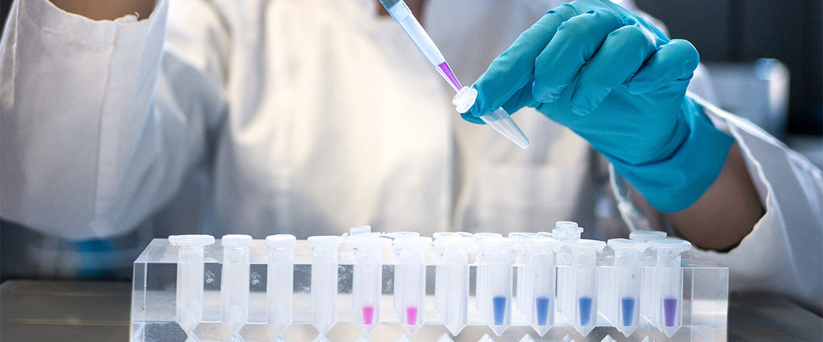 A chemist or scientist hands are shown in a laboratory setting, testing different chemicals in testing tubes.